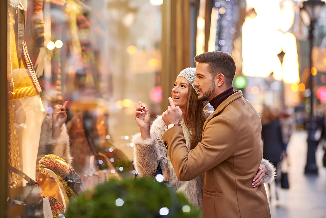 A young couple walking on the street and checking the storefront with Christmas decoration